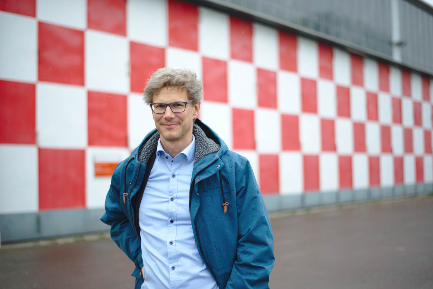 Herr Diehl steht vor den Karo-gemusterten Toren des alten Hangars