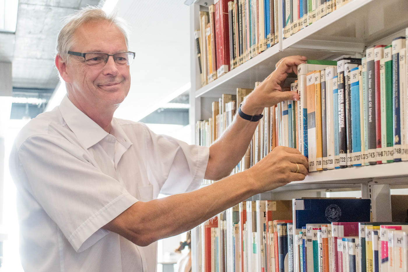 Herr Neumärker sucht Buch aus Regal