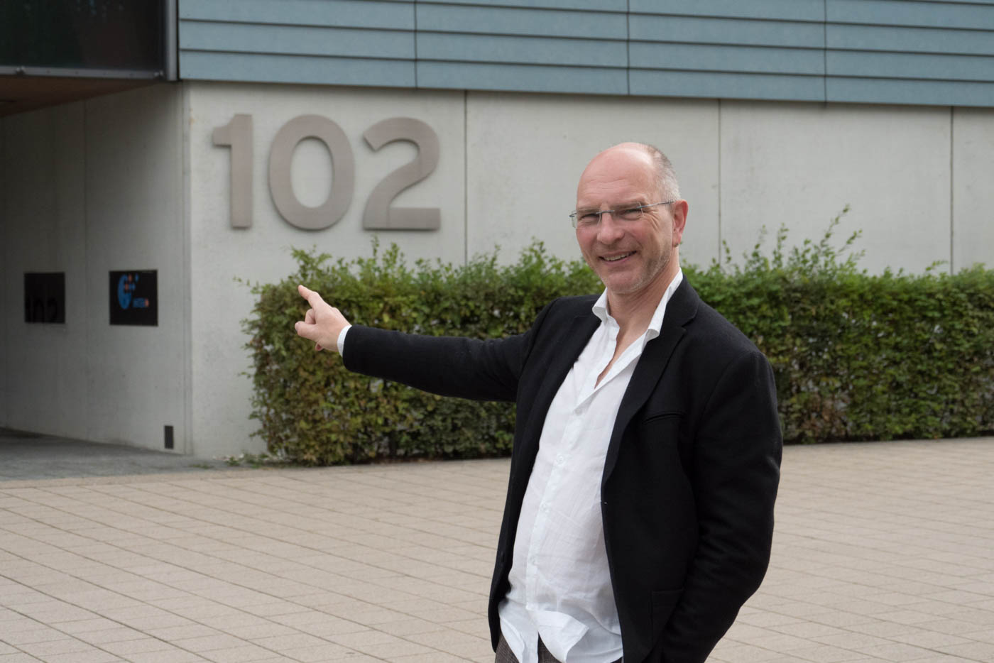 Herr Stieglitz weist auf Gebäude 102