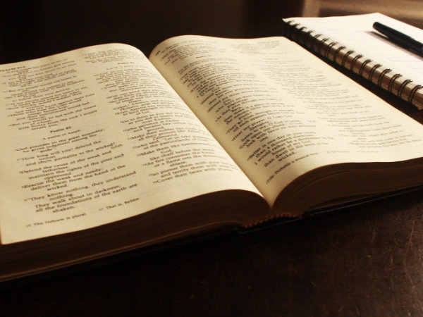 Aufgeschlagene Bibel nebendran liegt ein Notizblock