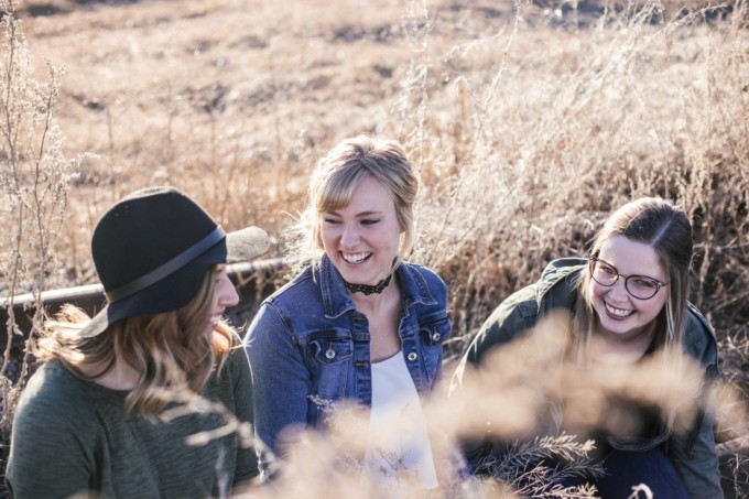 Drei junge Frauen unterhalten sich lachend - in der Natur sitzend